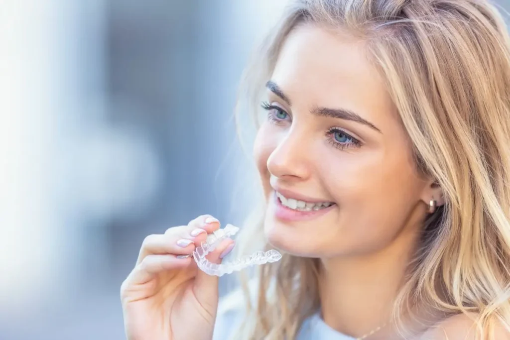 niña sonriente sosteniendo alineadores Invisalign