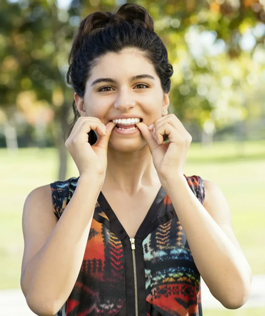 adolescente sonriente colocándose sus alineadores Invisalign escalados